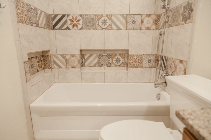 modele de salle de bain aux murs en carrelage imitation carreaux de ciments de couleurs beige avec petite baignoire douche