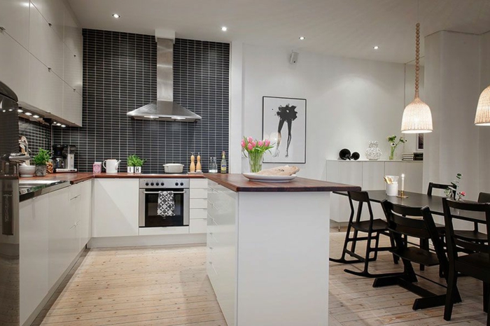 comptoir de cuisine dans une cuisine scandinave et sol en planches, grande table de repas noire, crédence gris anthracite