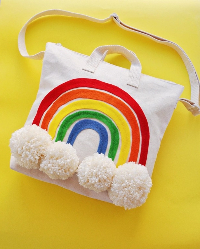 exemple de sac cabas personnalisé avec bandeau de tissu colorées à design arc en ciel et pompons en laine blancs