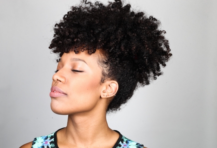 exemple de coiffure de style afro puff avec volume sur le haut et mèches tombantes devant, maquillage contouring naturel pour peau mate