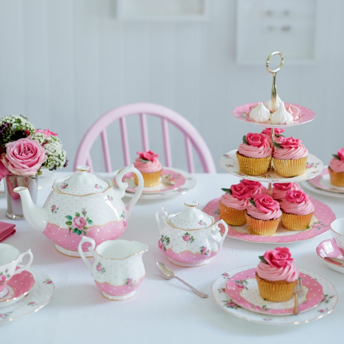 joli gâteau de petits cakes, ustensiles en rose et blanc, petit bouquet de roses, table blanche, chaise rose