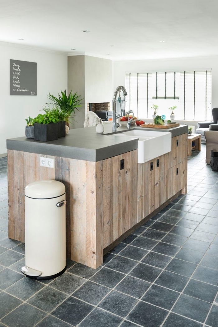 plan de travail ilot central en béton et planches de bois au look rustique avec une zone de lavage dans une cuisine conviviale ouverte sur le salon