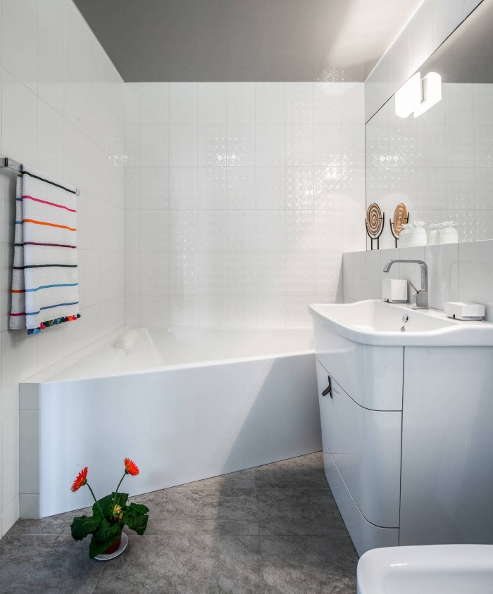 idée décoration de salle de bain blanche au plancher en carrelage imitation béton avec serviette colorée et fleurs