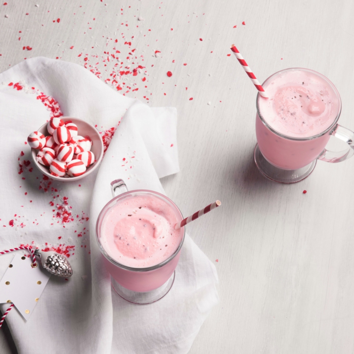 milkshake sucré rose avec bonbons sucrés colorés, deux verres de milkshake, petit cone argenté, couverture blanche