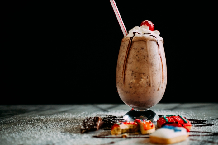 milkshake chocolat versé dans un verre et décoré de délices différentes, comment faire un milkshake