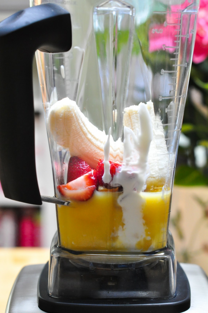 préparation d'un smoothie banane avec jus de citron et fraises mis dans le blender