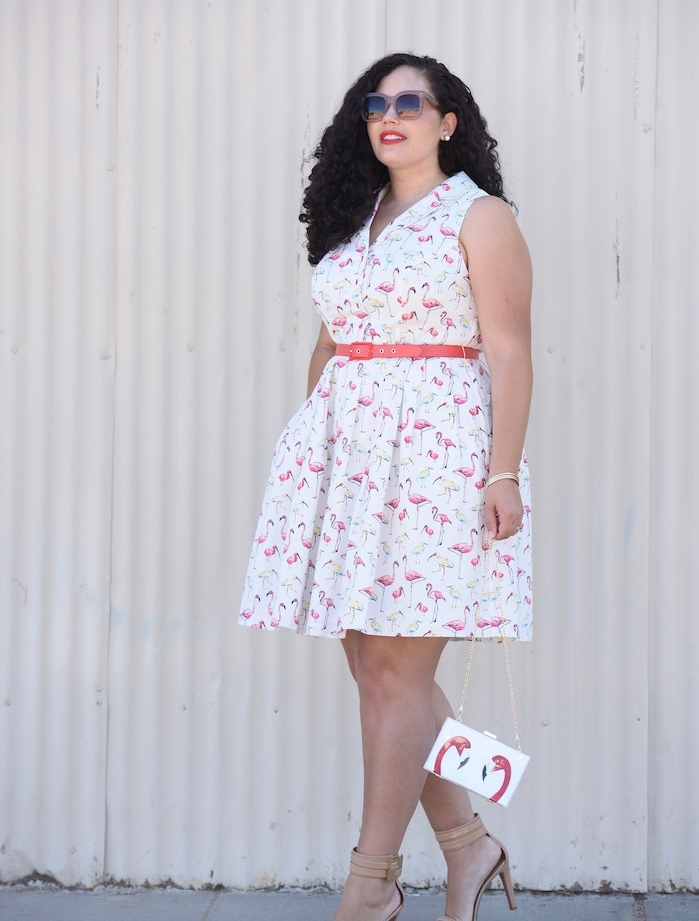 imprimé flamant rose sur une robe blanche avec ceinture sur la taille, col en v et pochette flamant rose, lunettes de soleil