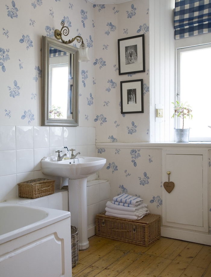 salle de bain habillée de papier peint, sol en parquet bois clair, lavabo console blanc, miroir vintage, baignoire à poser blanche