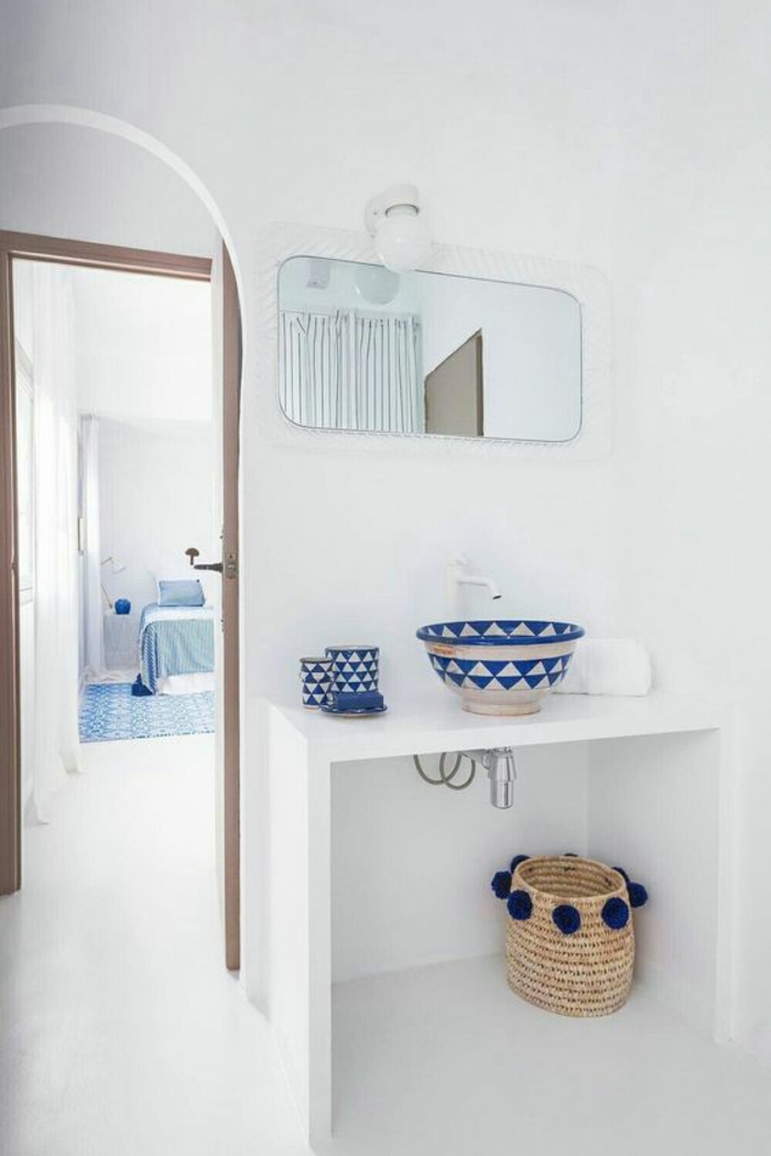 salle de bain 5m2, deco salle de bain zen, table blanche, panier de rangement en paille tressée avec des pompons en bleu marine tout autour, carrelage blanc