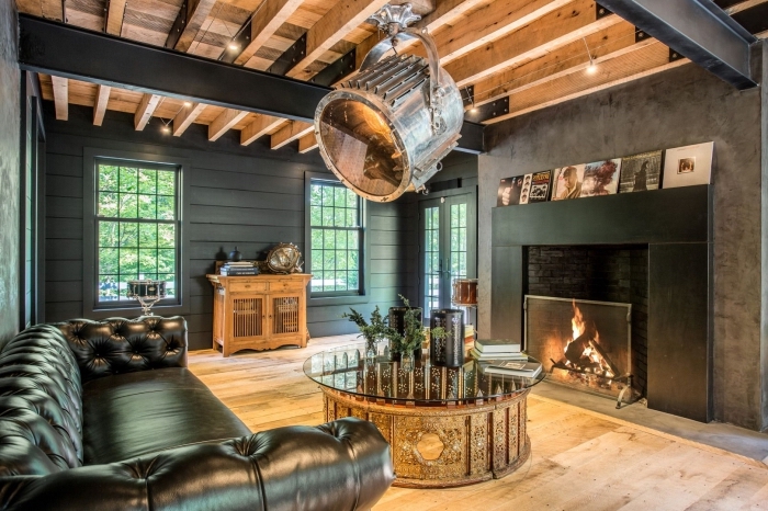 design intérieur moderne dans un salon gris anthracite avec cheminée noire et plafond en poutres de bois exposées