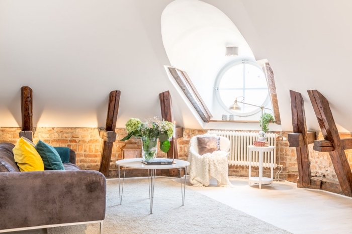 design intérieur moderne et cozy dans un salon sous pente avec murs blancs à déco briques rouges et poutres de bois apparentes