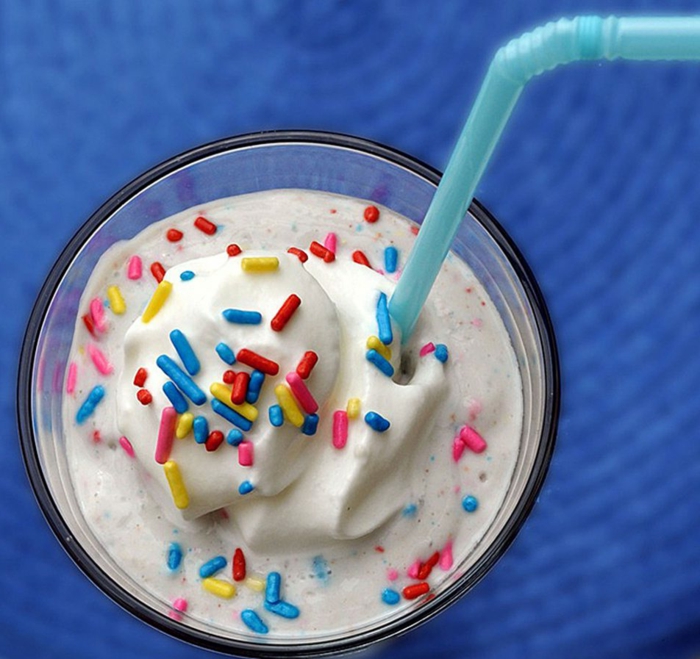 verre de milk shake, boisson protéinée, décoration avec petites batons gourmandeset paille bleue