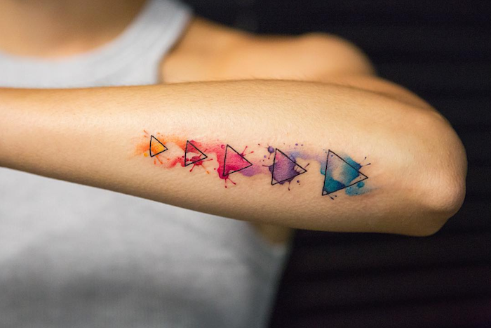 tatouage aquarelle triangles noirs et taches de couleurs sur l'avant bras