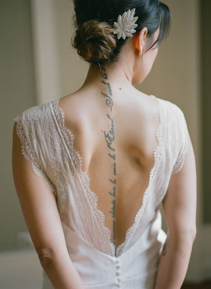une robe de mariée dos nu en dentelle qui met en valeur le tatouage phrase sur la colonne vertébrale 