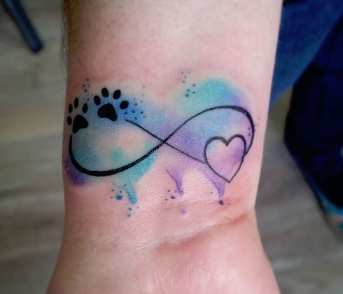 petite tatouage symbole de l'infini avec coeur et pieds de chiens sur fond aquarelle turquoise et violet
