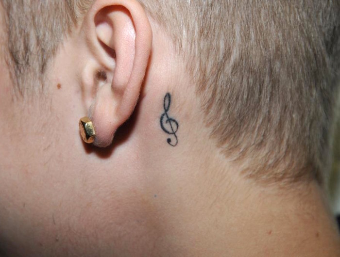 petit tatouage discret clé de sol fine sur la nuque derrière l'oreille homme