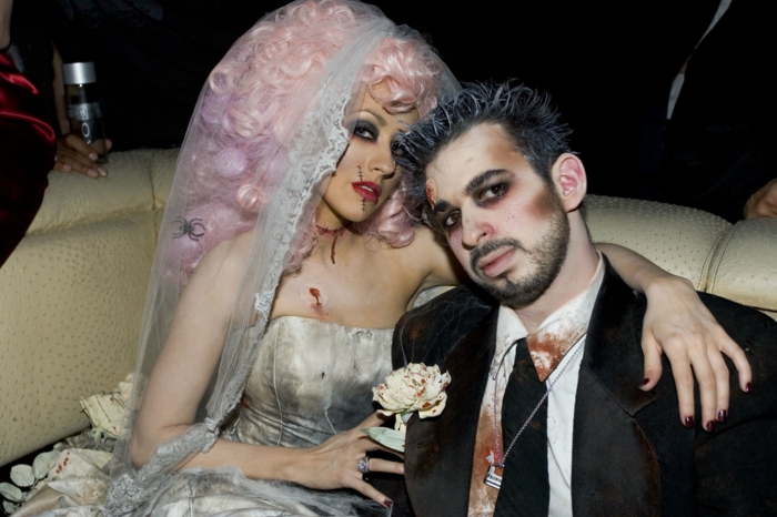 Christina Aguilera en robe de mariée, robe bustier, voile long, perruque rose, costume et cravate noirs, chemise blanche tachée de sang