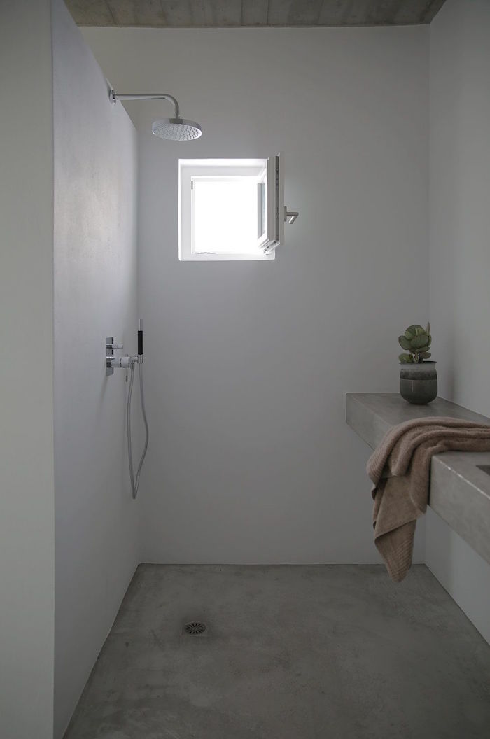 salle de bain en dur avec sol et murs en Tadelakt clair dans douche italienne avec petite fenetre