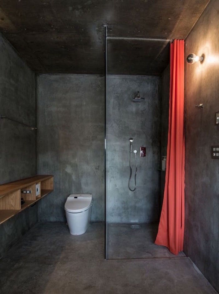 petite salle de bain fermé avec revêtement ciment gris foncé sol murs avec douche italienne en monobloc