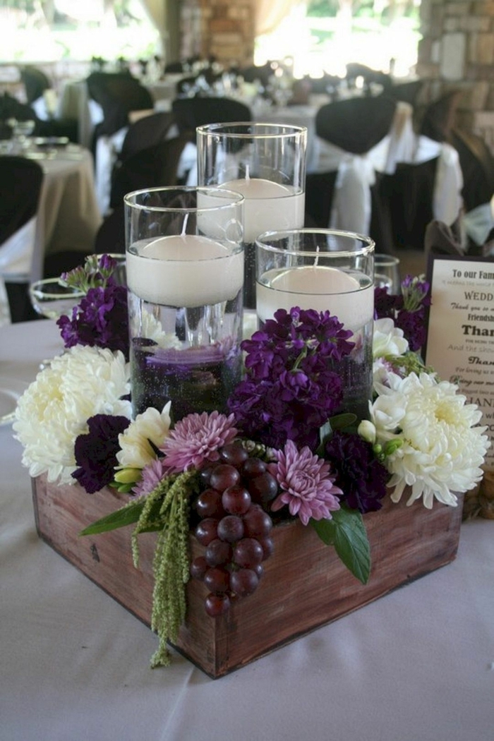 bougeoirs en verre avec bougies flottantes, fleurs rustiques et vigne dans une petite caisse de bois