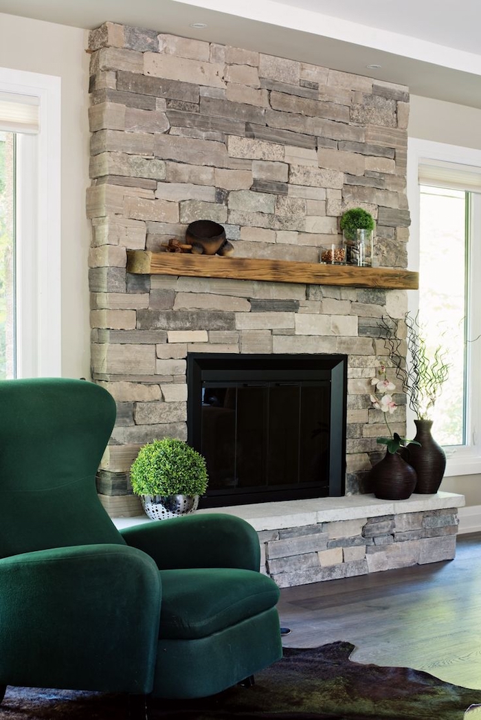 manteau de cheminée décoratif en pierre de parement couvrant le mur et etagere en bois, fauteuil design vert foncé