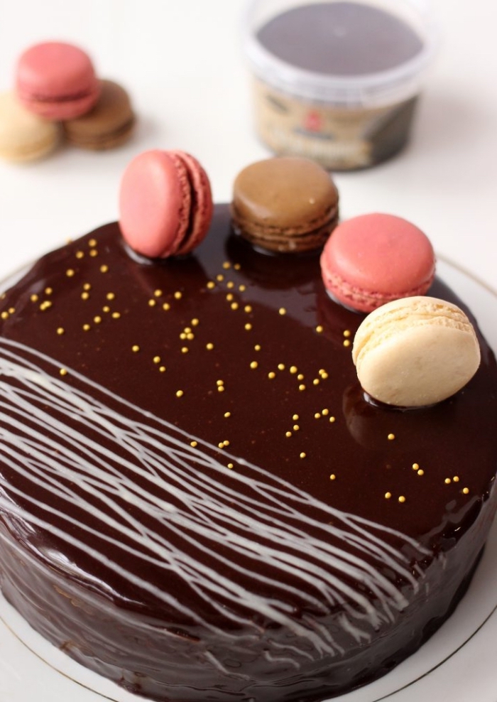 recette de gâteau au glacage miroir chocolat, décoré de macarons vanille et fraise