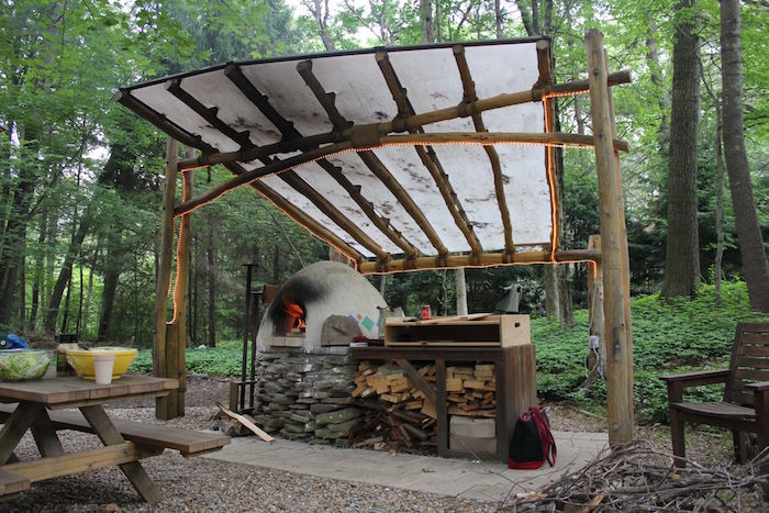 cuisine couverte d'extérieur rustique fait main avec four à bois en pierres et toit pour pique nique