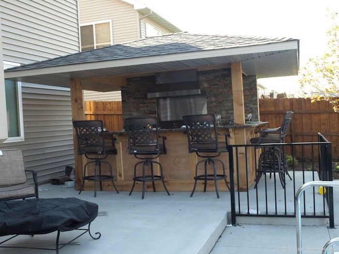 cuisine d'été extérieure couverte en bois avec bar et mur en pierre sur le balcon