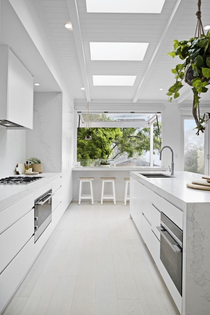 décoration épurée dans une cuisine ouverte équipée d'îlot avec évier et plan de travail à design marbre blanc