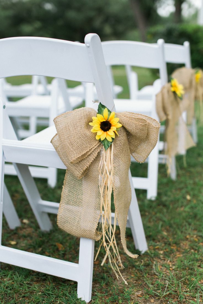 mariage campagnard qui se déroule en plein air, chaises blanches, rubans de jute décorés de tournesols