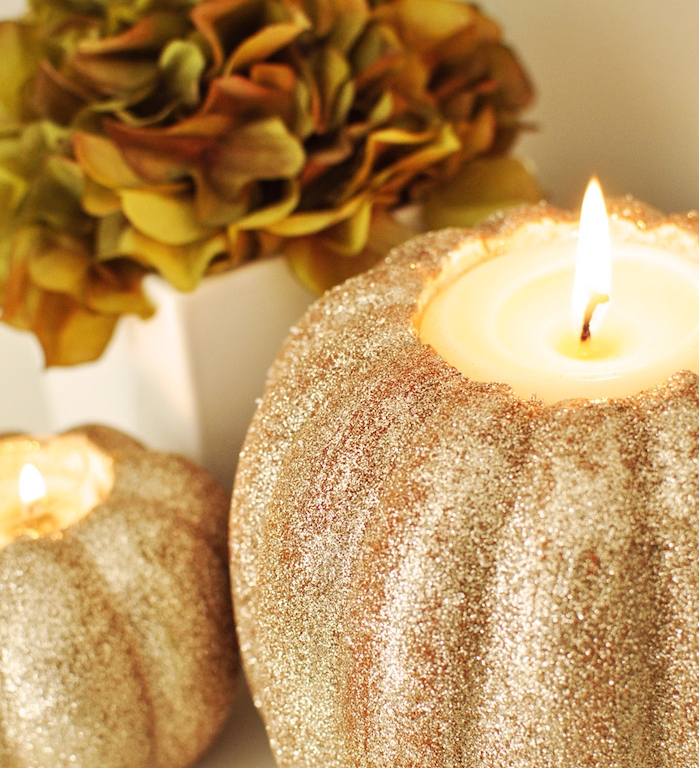 bricolage halloween facile en citrouille décorée de paillettes avec une bougie à l intérieur et un bouquet de fleurs à côté
