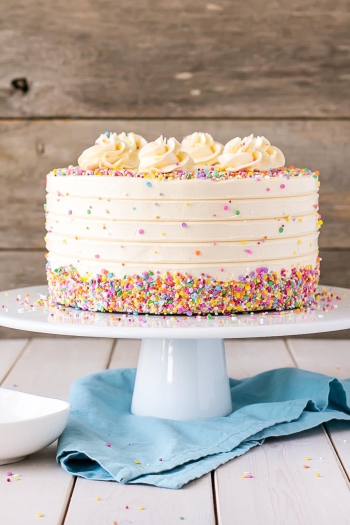 un gâteau d'anniversaire recouvert de glacage blanc vanille au beurre saupoudré de vermicelles colorées