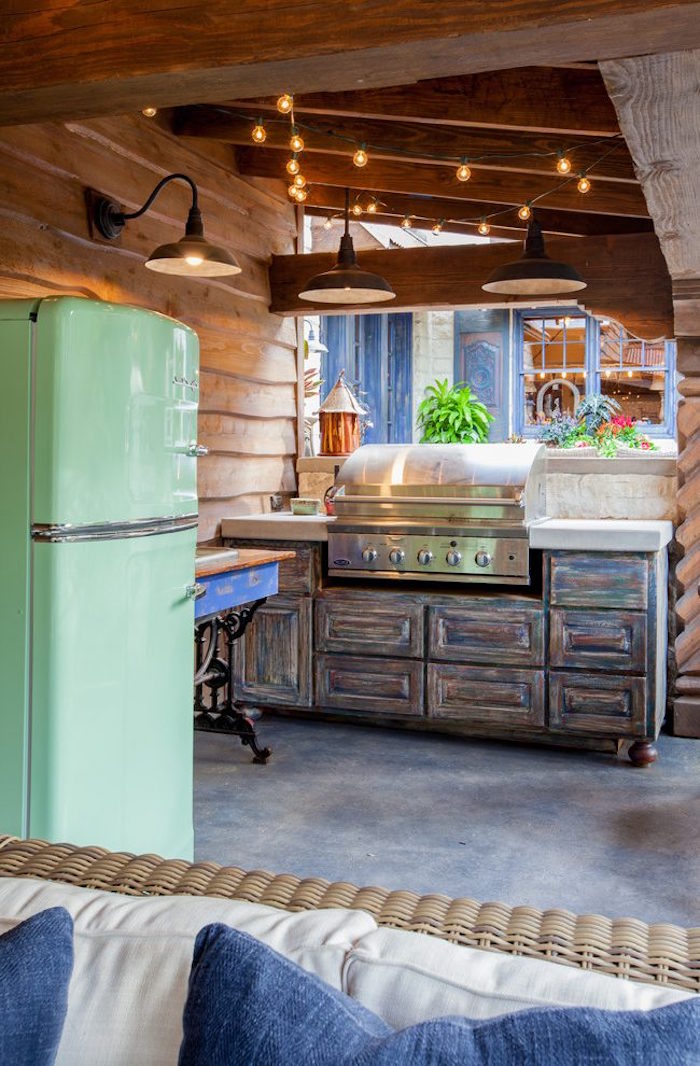terrasse avec cuisine exterieure bois et sol beton avec salon et meubles style retro rustique