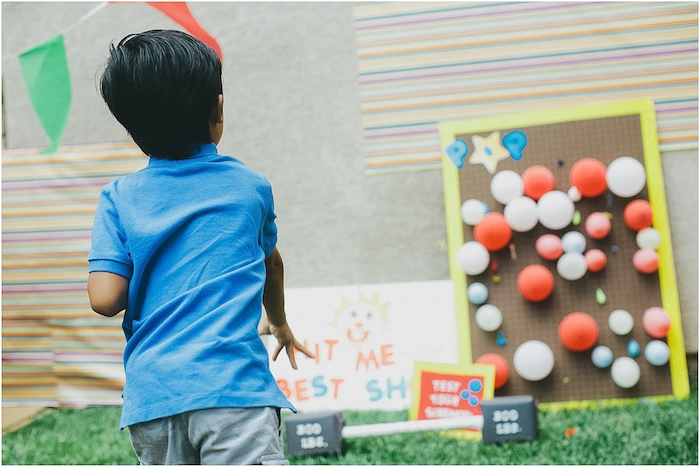 exemple de jeu de tir pour enfant sur des ballons colorés posés sur un tableau en bois, jeux anniversaire 7 ans