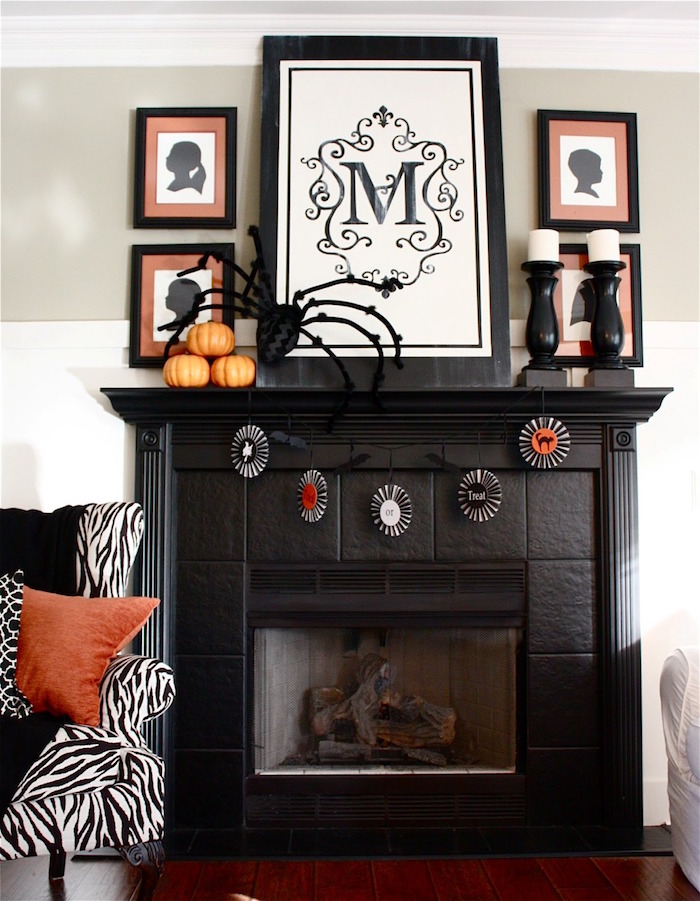 cheminée noire mat avec cadre en carrelage et déco halloween orange avec mini citrouilles, cadres dessins silhouette et canapé zébré