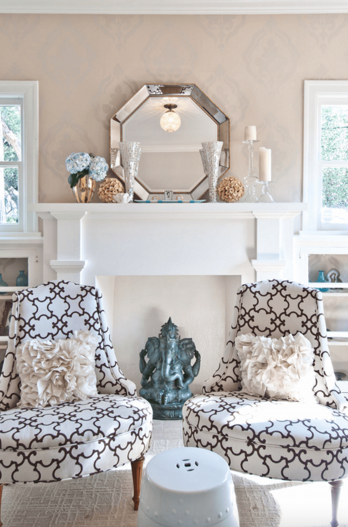 manteau de fausse cheminée décorative blanc comme support objets déco bougeoirs, plateau miroir, fauteuils rétro design brodés avec coussins vintage