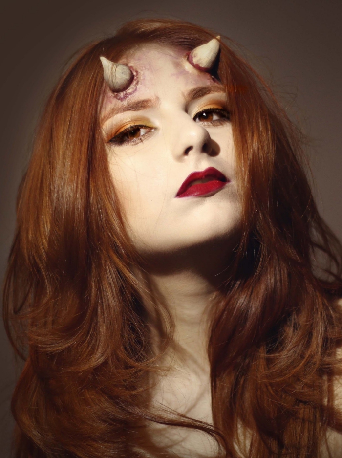 un maquillage de diablesse rouge-orange glamour avec des fausses cornes collées au front
