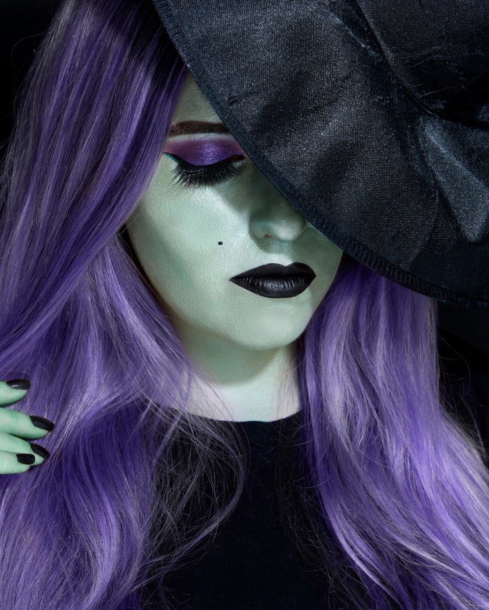 un maquillage sorciere halloween glamour avec visage peint en vert, des yeux fardés de violet et une bouche noire mat