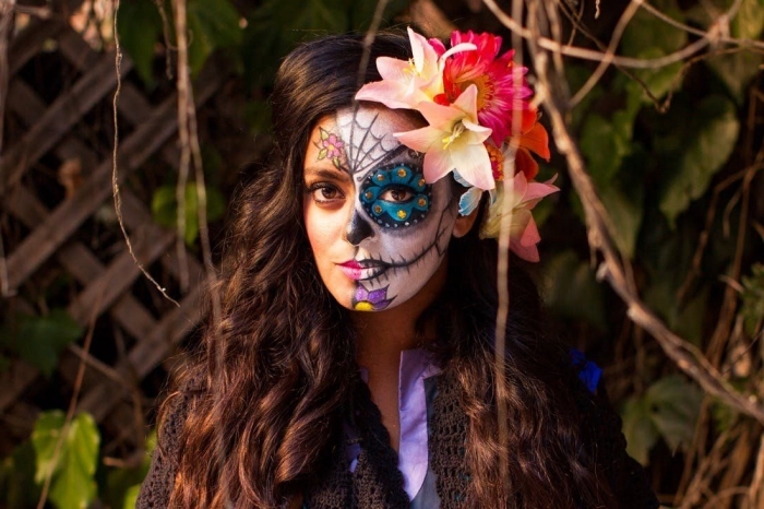 un maquillage tête de mort mexicaine réalisé sur la moitié du visage et coiffure avec fausses fleurs 