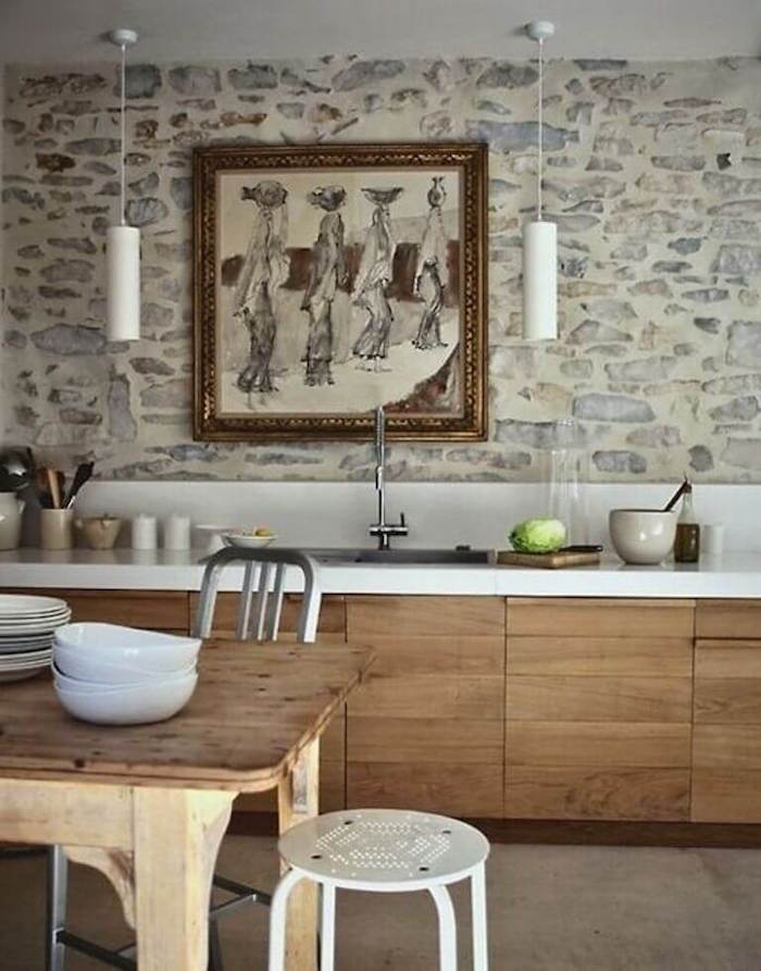 mur en pierres rénové à la chaux dans cuisine avec meubles en bois anciens pour déco rustique