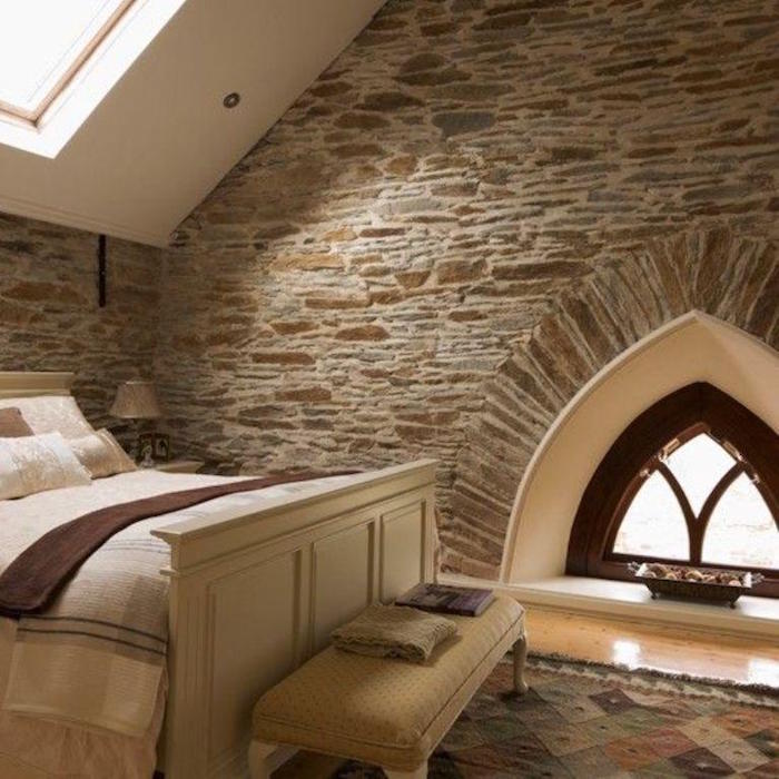chambre dans étage de vieille maison en pierre avec petite fenetre et velux