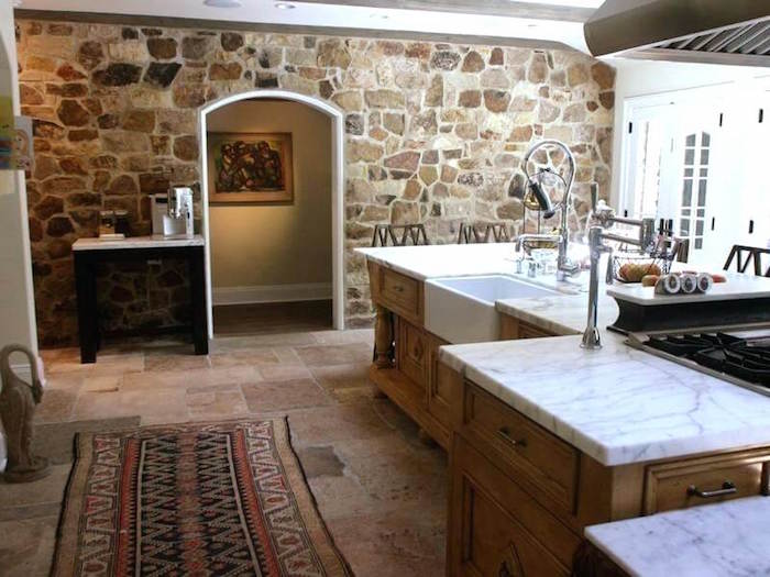 mur en pierre intérieur rénové à la chaux dans grande cuisine avec ilot central