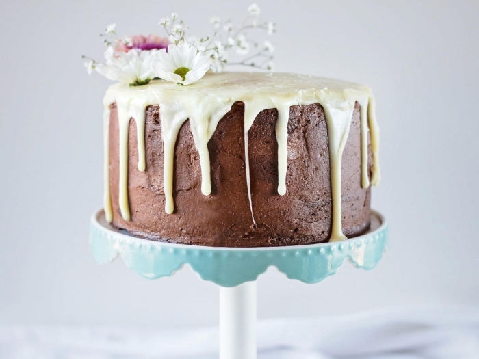recette de gâteau triple chocolat au glacage chocolat blanc coulant, avec une simple décoration de fleurs champêtres