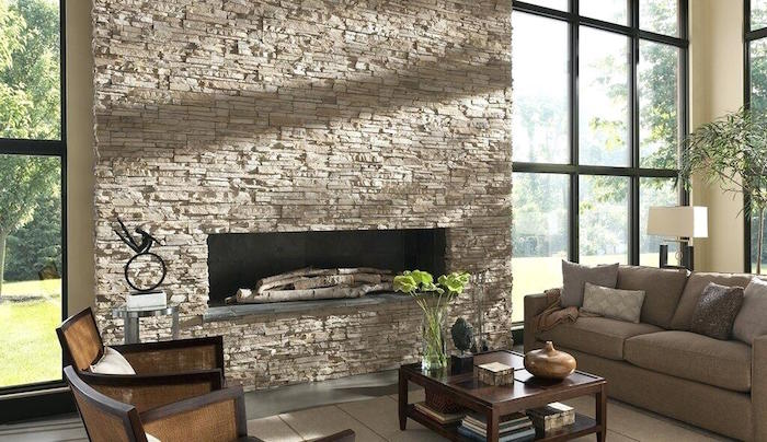 pierre de parement beige recouvrant mur et conduit de cheminée dans grand salon avec baies vitrées