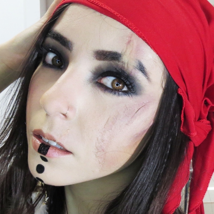 joli maquillage pirate femme sauvage avec fausse cicatrice et des yeux charbonneux, portant un foulard rouge à la tête