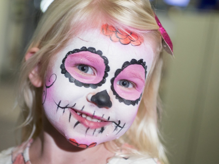 maquillage halloween mexicain, petite fille blonde avec un maquillage squelette rose et noir