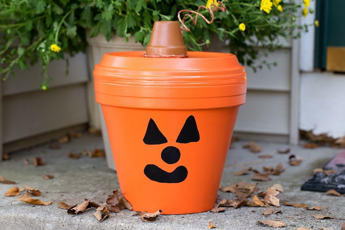 jack o lantern motif citrouille sur un pot en terre cuite avec couvercle orange et dessin à l indélébile noir sur pot