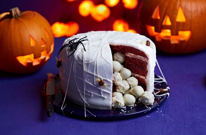 gateau halloween facile rempli de bonbons, idée gâteau au chocolat avec glaçage blanc et déco figurines d'araignées