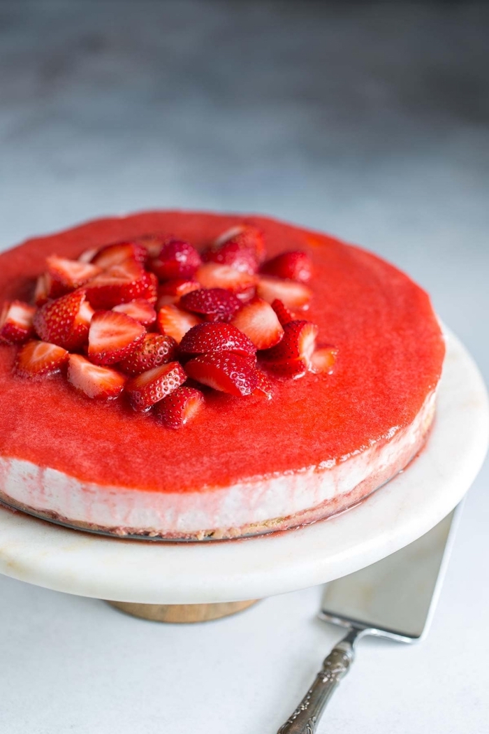 une variante sans cuisson du cheesecake américain classique à la fraise, au fromage frais et au glaçage miroir de fraises