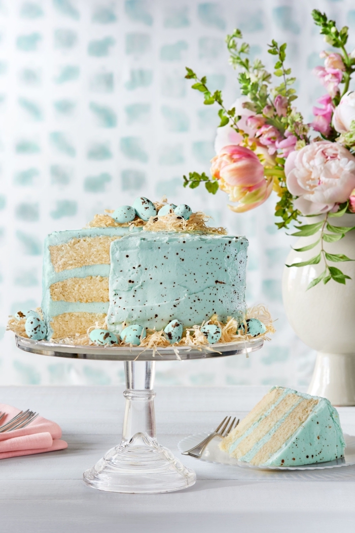 idée originale pour un gâteau de pâques vanille et noix de coco, recouvert d'un nappage gateau coloré bleu pastel et décoré avec des oeufs au chocolat